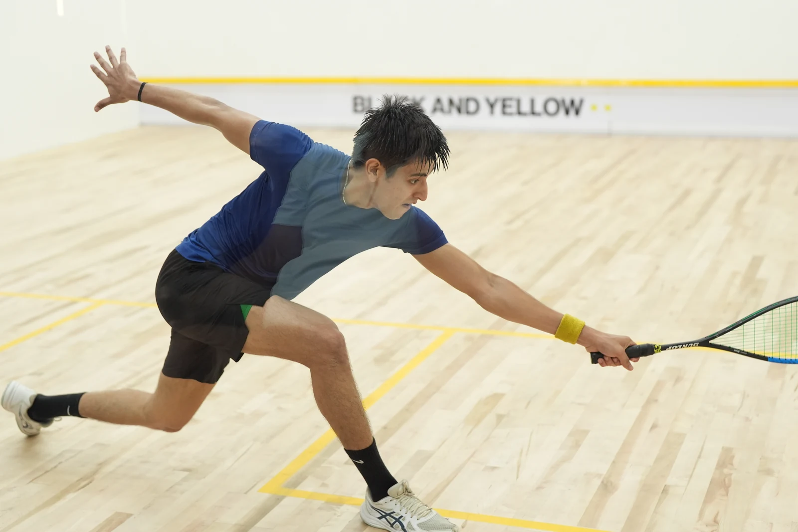 A squash player lunging towards the ball during a rally at BAY.