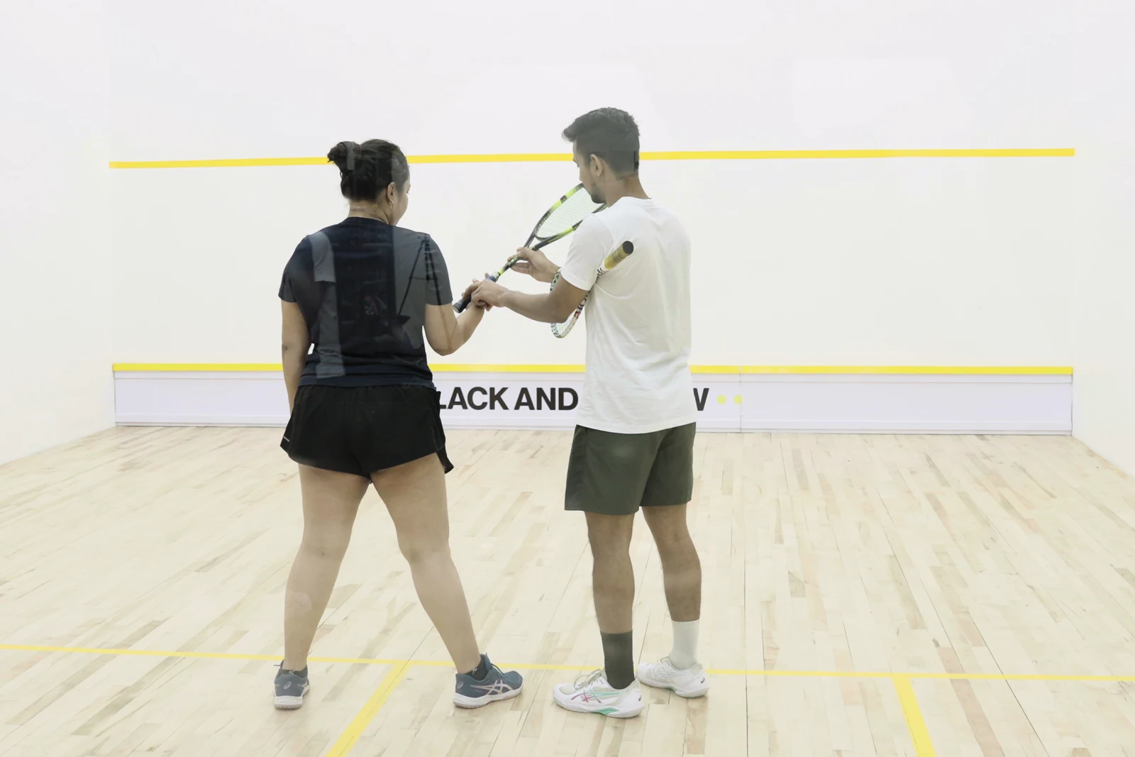 A coach guiding a developing player’s racket position on the BAY court.