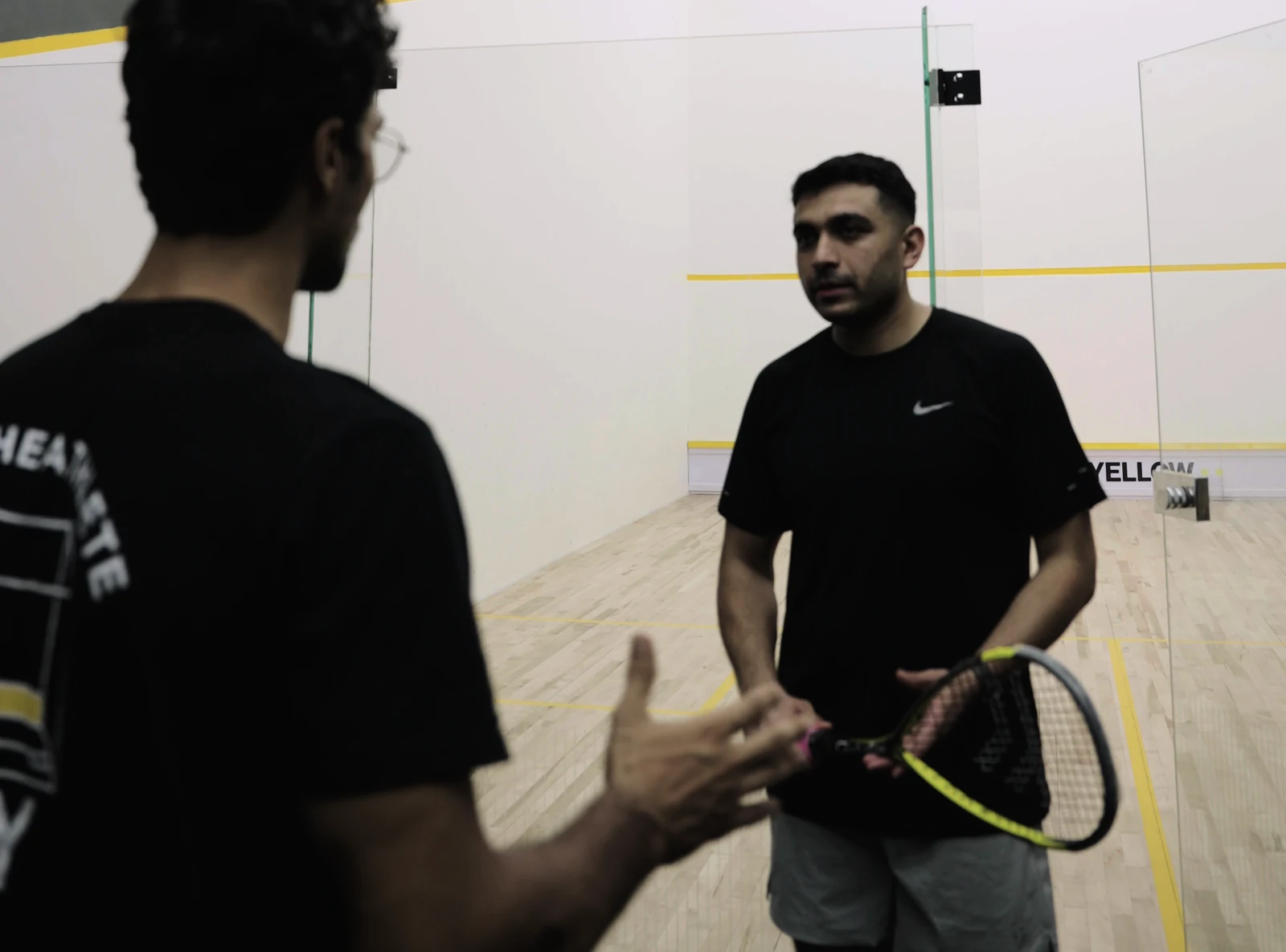 A player talking with a coach beside the BAY squash court.