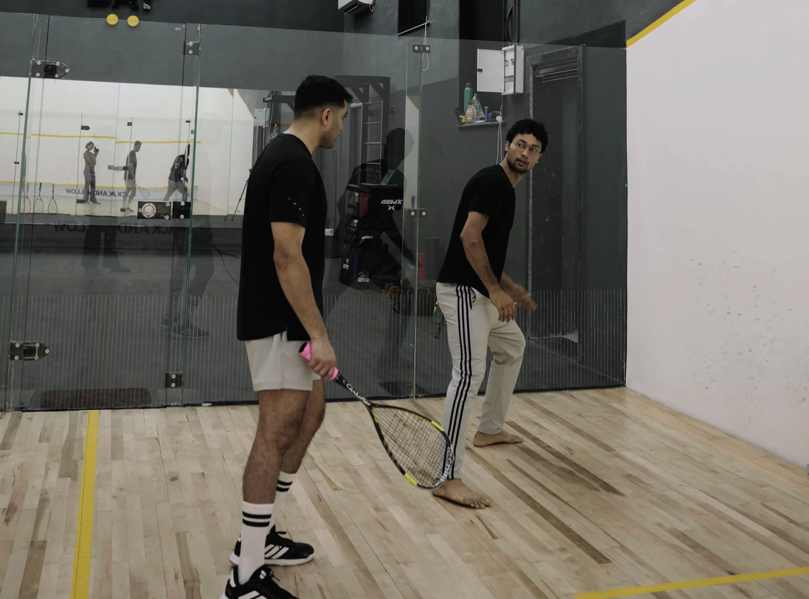 A coach and player checking squash stance on the BAY court.